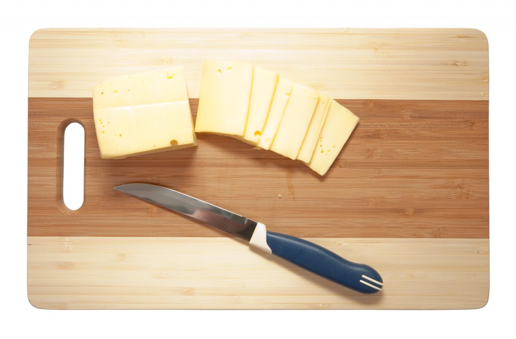 Chef's knife hopping an cheese on an wooden cutting board - white background